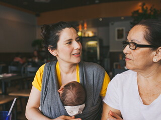 Une mère portant son bébé discute avec une femme âgée.
